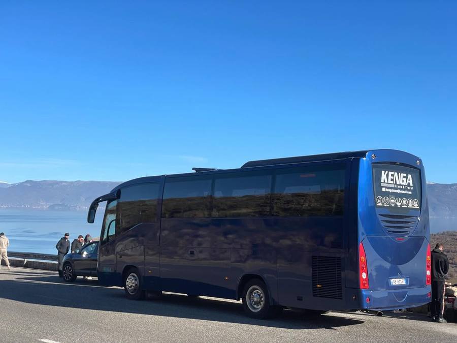 Autobus i Kenga Bus i ndalur në rrugën buzë liqenit, me male në sfond