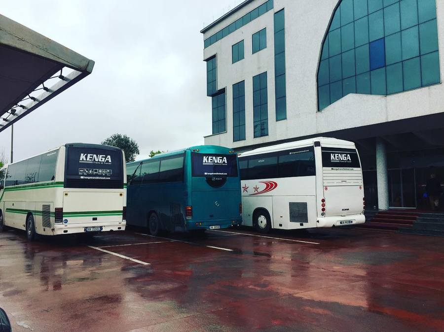 Tre autobusë të Kenga Bus të parkuar para një hoteli