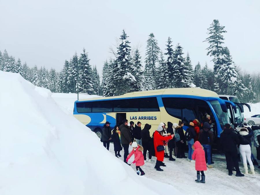 Udhëtarë duke hipur në autobusin e Kenga Bus në një pyll me borë